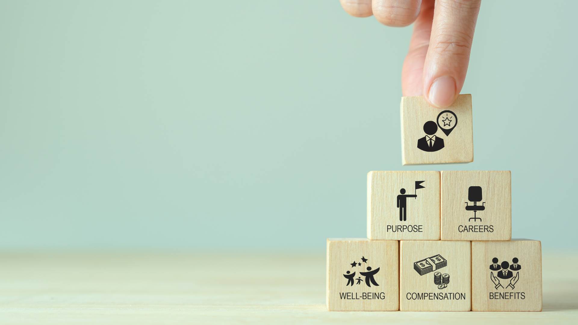 Wood blocks stacked in a pyramid with different employee management terms on them.