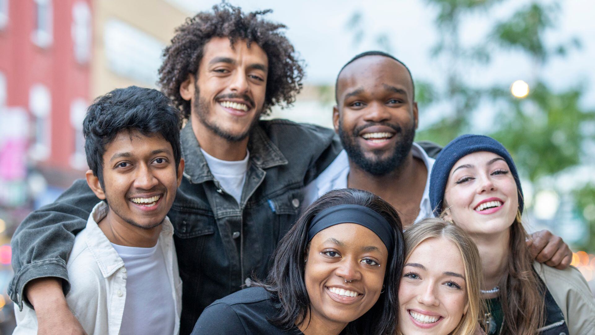 Siz young adults smiling and hugging. Three young men and 3 young women.